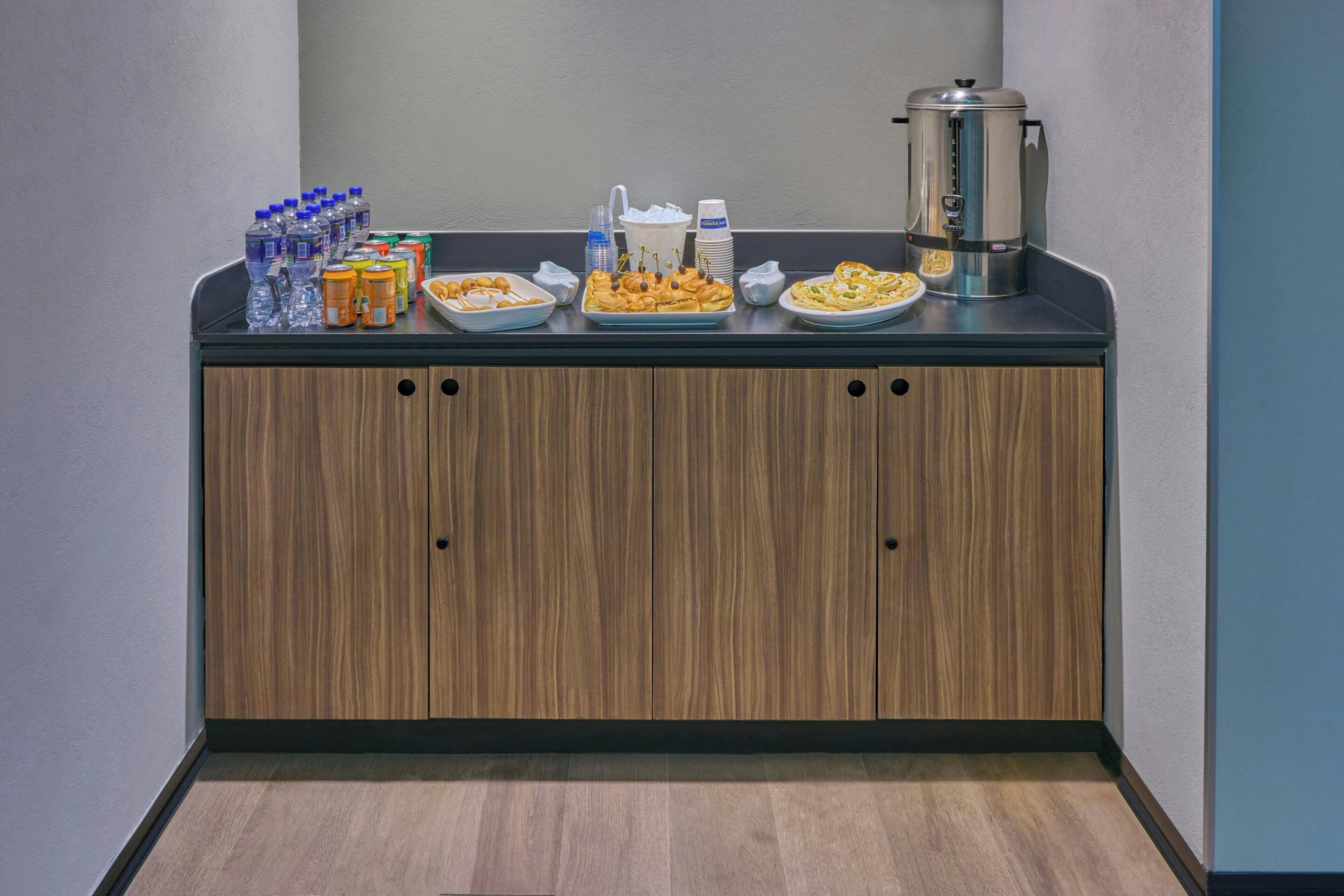 A buffet setup with water bottles, juice, and various food items on a counter.