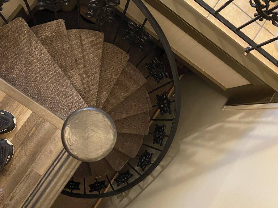 A spiral staircase with ornate metal railings and a wooden handrail.