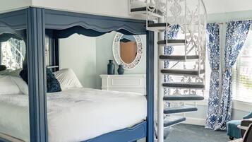 Une chambre à coucher avec un lit à baldaquin, une commode blanche, un miroir et un escalier en colimaçon.