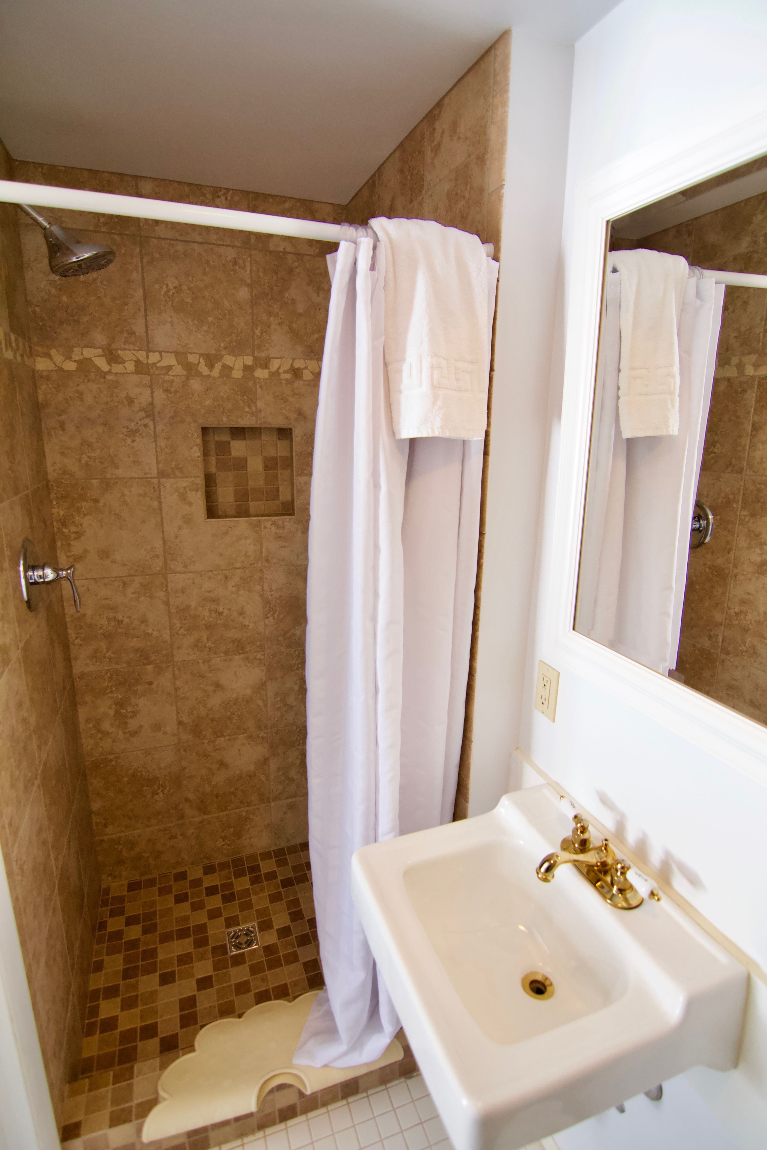 A bathroom with a shower, a sink, and a mirror.