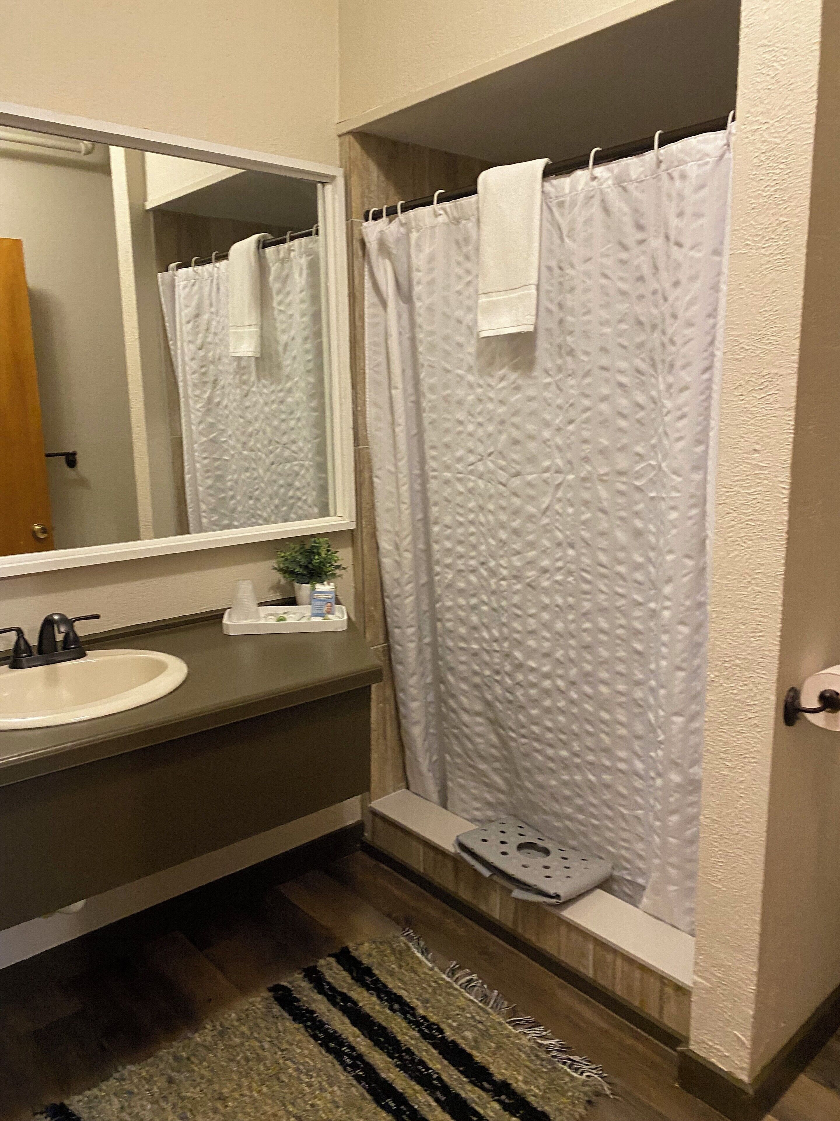 A bathroom with a sink, mirror, and shower curtain.