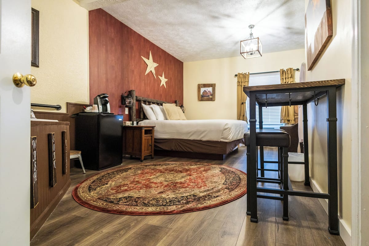 Een slaapkamer met een bed, nachtkastje, en een groot vloerkleed.