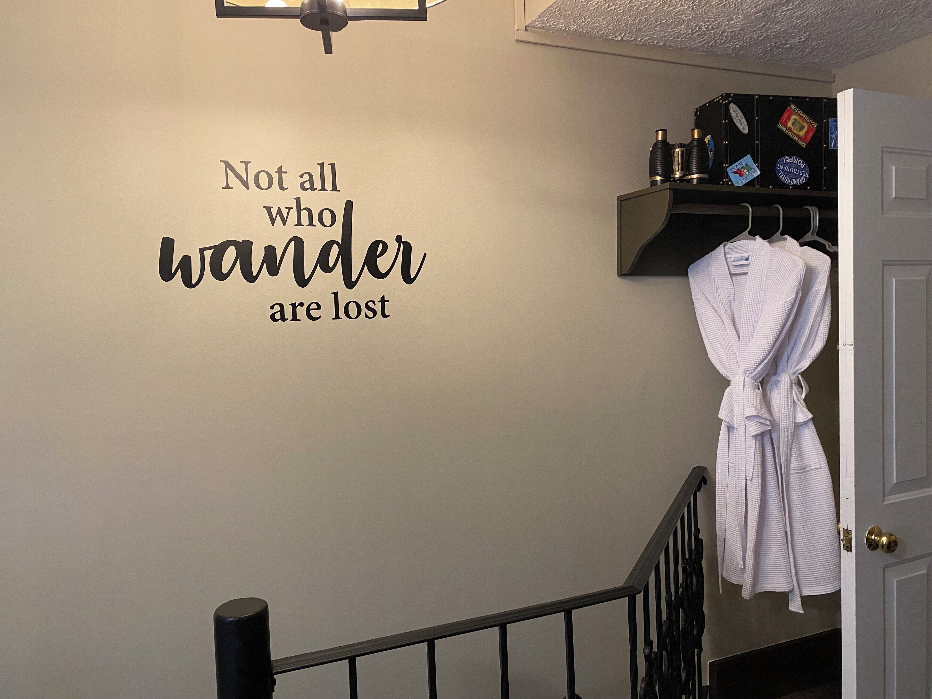 A wall with a motivational quote, a staircase, and a robe hanging on a rack.