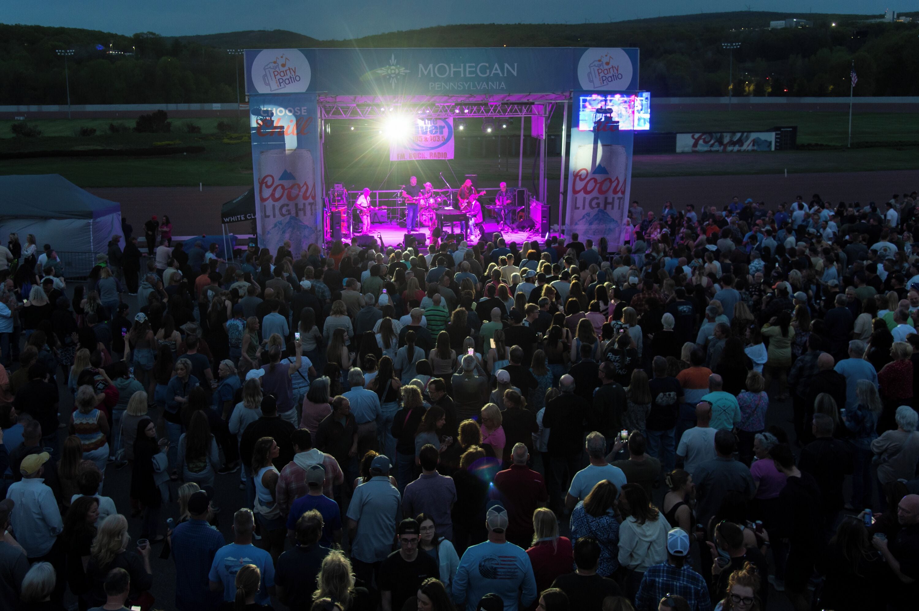 Un escenario de concierto grande al aire libre, con una multitud de personas en primer plano.