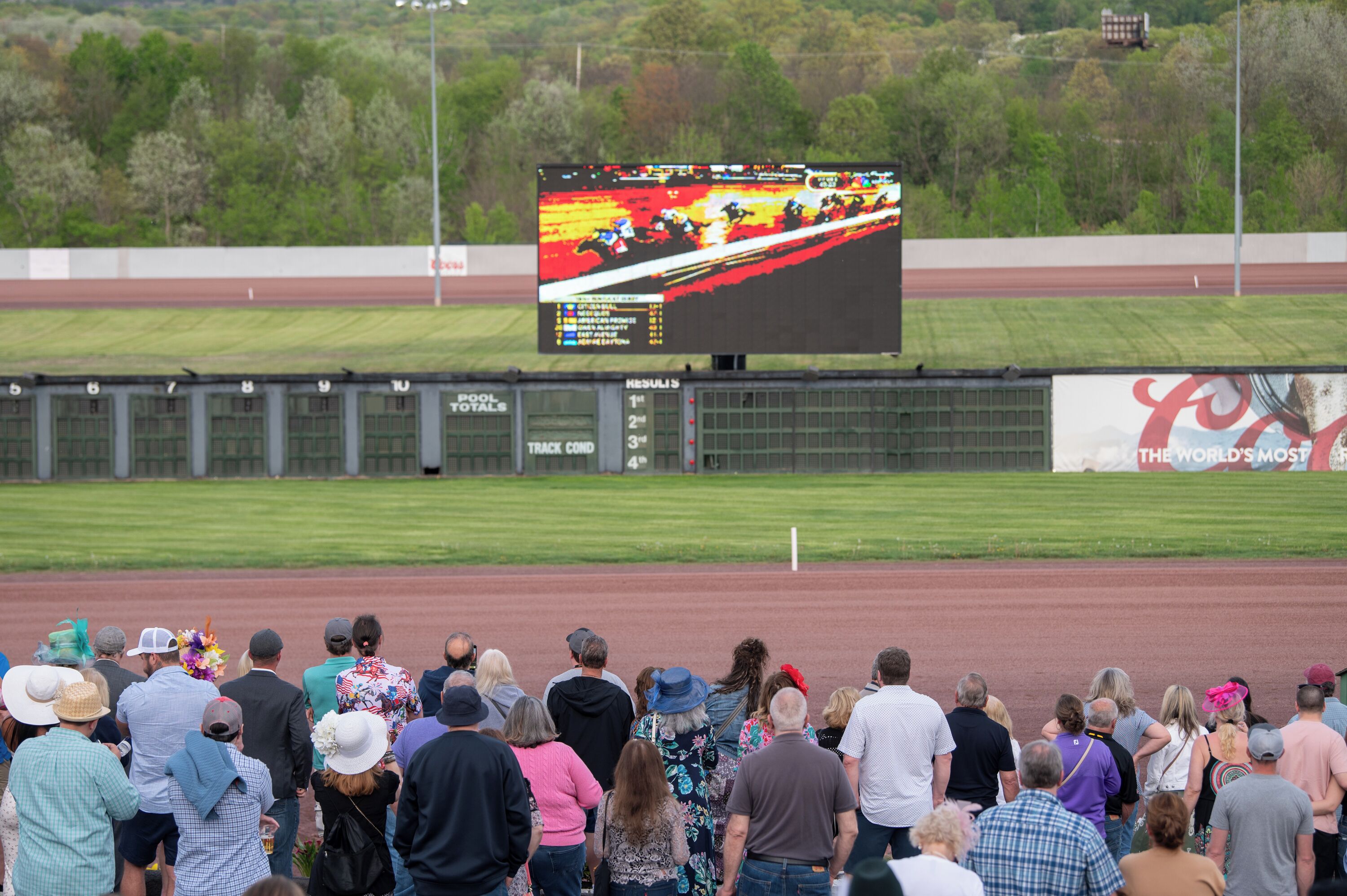 Una pista de carreras con espectadores y un marcador digital grande que muestra los resultados de la carrera.