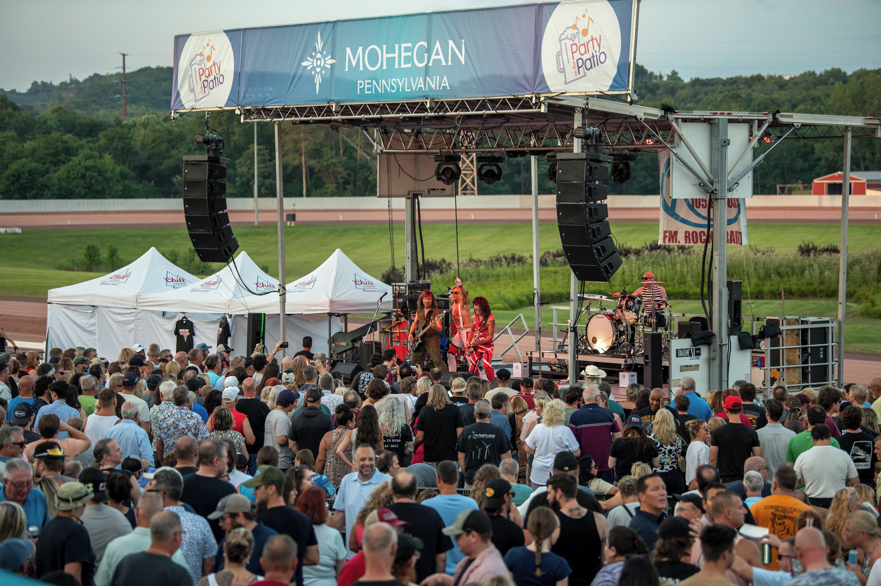 A stage with a band performing, surrounded by a crowd of people.