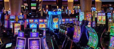 Un casino con numerosas máquinas tragamonedas y mesas de juego.