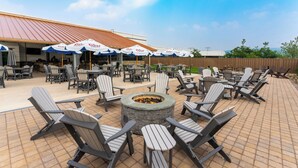 An outdoor patio area with Adirondack chairs, a stone fire pit, and umbrellas branded with "Coors Light."