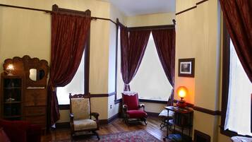 A room with two chairs, a small table with a lamp, and a wooden cabinet.