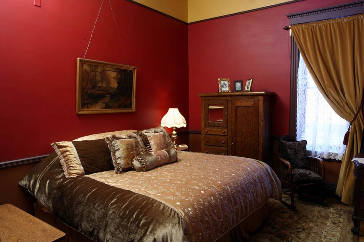 A bedroom with a large bed, a wooden dresser, a chair, and a painting on the wall.