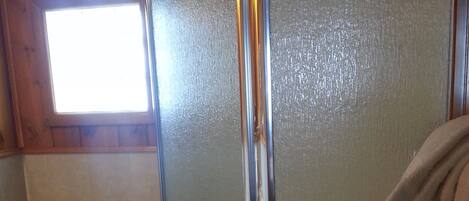 A bathroom with a toilet, a glass shower enclosure, and a towel hanging on the wall.