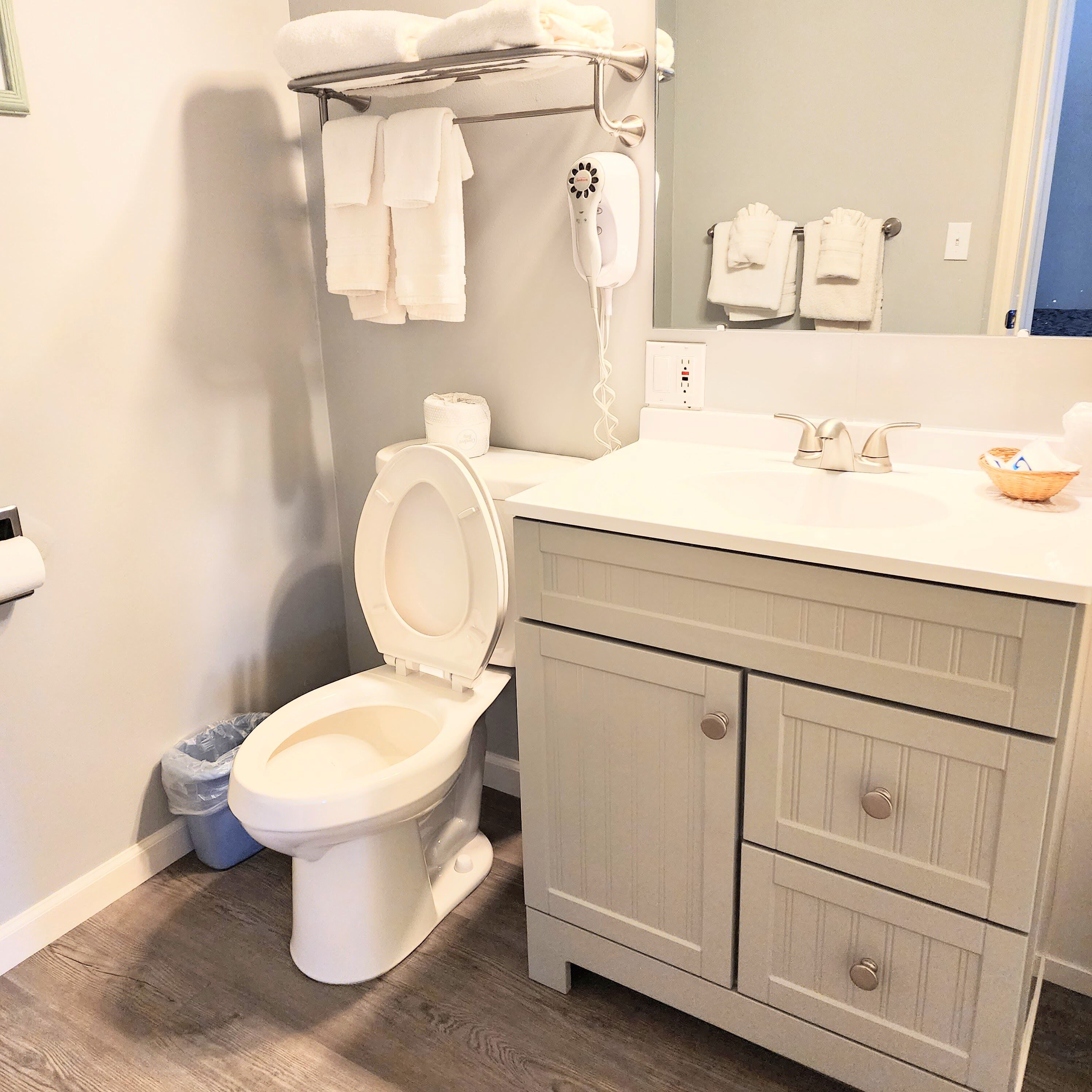 A bathroom with a toilet, a sink, a mirror, and a towel rack.