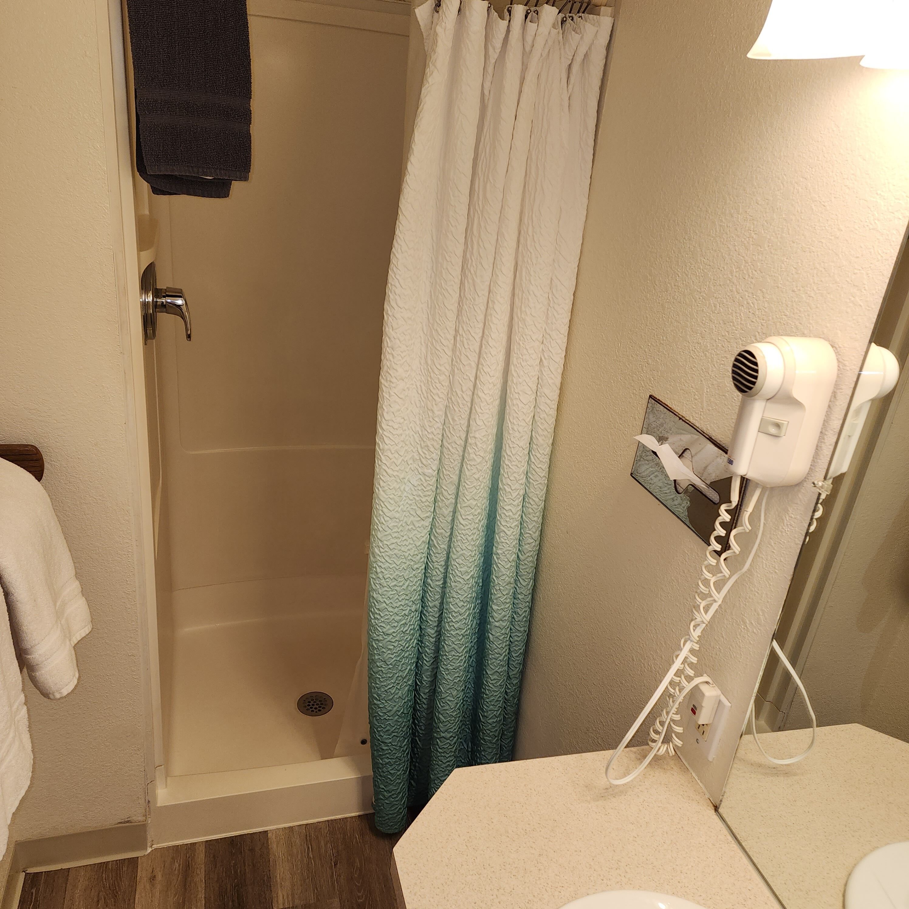 Casa de banho com chuveiro, secador de cabelo e porta-toalhas.