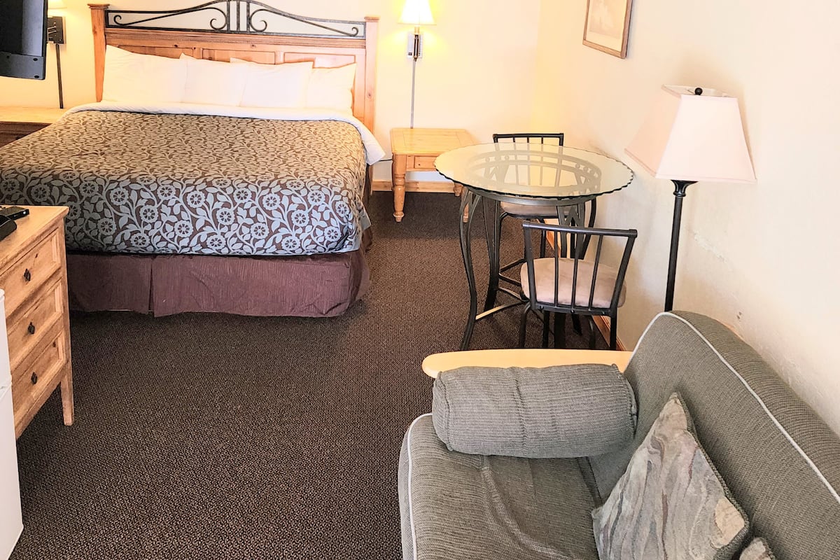 Ein Hotelzimmer mit einem Bett, einem kleinen runden Tisch, einer Couch und einem Fernseher.