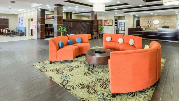 A hotel lobby with orange sofas, a reception desk, and a patterned rug. - Comfort Suites Cotulla near I-35 (Cotulla)