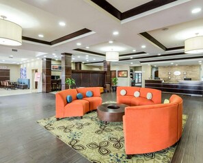 A hotel lobby with orange sofas, a reception desk, and a patterned rug. - Comfort Suites Cotulla near I-35 (Cotulla)