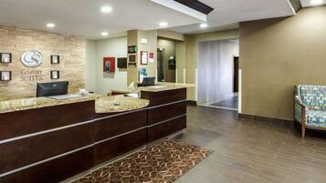 A hotel reception area with a reception desk, a patterned rug, and a chair.