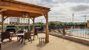 A covered outdoor area with a barbecue grill, seating, and a pool. - Comfort Suites Cotulla near I-35 (Cotulla)