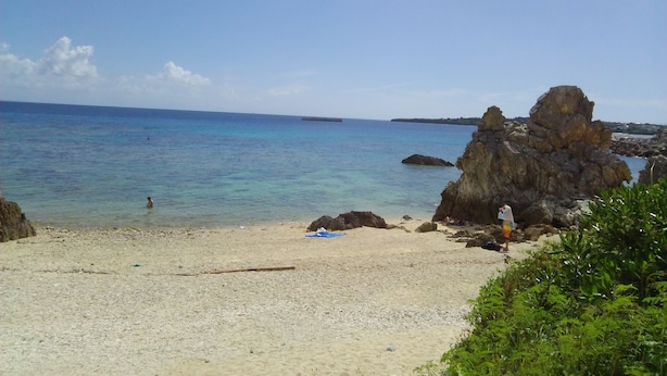A beach with clear turquoise water, rocky formations, and sparse vegetation. - SEVEN VILLAGE Motobu (Motobu)