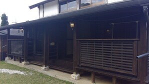 A wooden building with a covered porch, stone steps, and a metal railing. - SEVEN VILLAGE Motobu (Motobu)