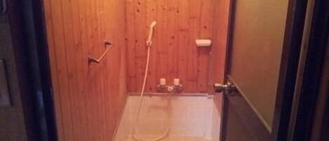 A wooden-paneled shower stall with a handheld showerhead and a toilet.