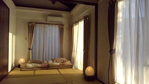 A traditional Japanese room with tatami flooring, a low bed with cushions, a shoji screen, and a paper lantern. - SEVEN VILLAGE Motobu (Motobu)