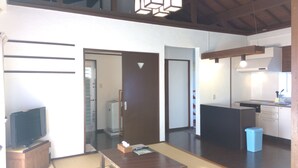 A modern kitchen with a built-in stove, a sink, and a refrigerator. There is a dining table with a few items on it. - SEVEN VILLAGE Motobu (Motobu)