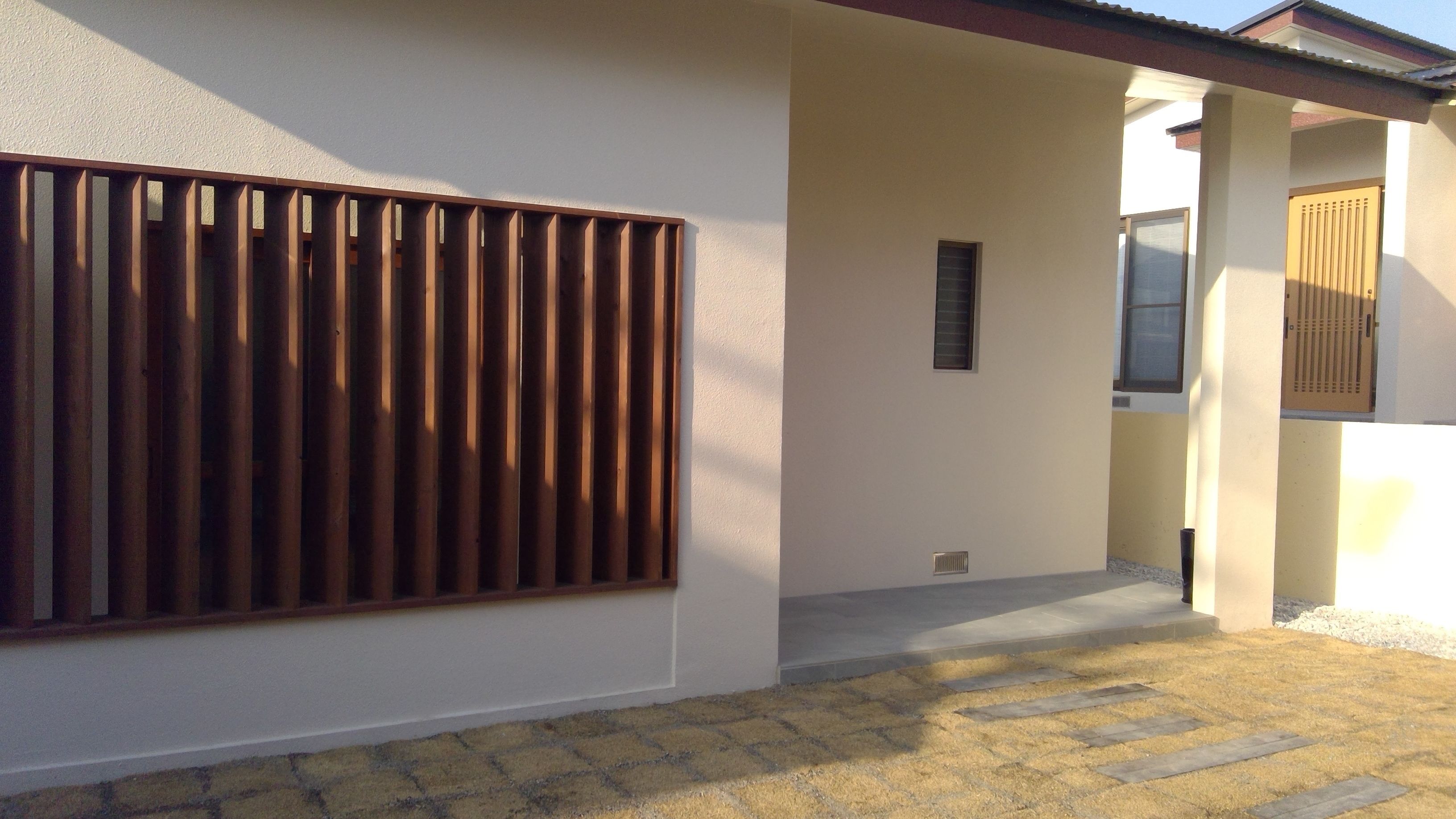A building exterior with a large window, a door, and a small vent.