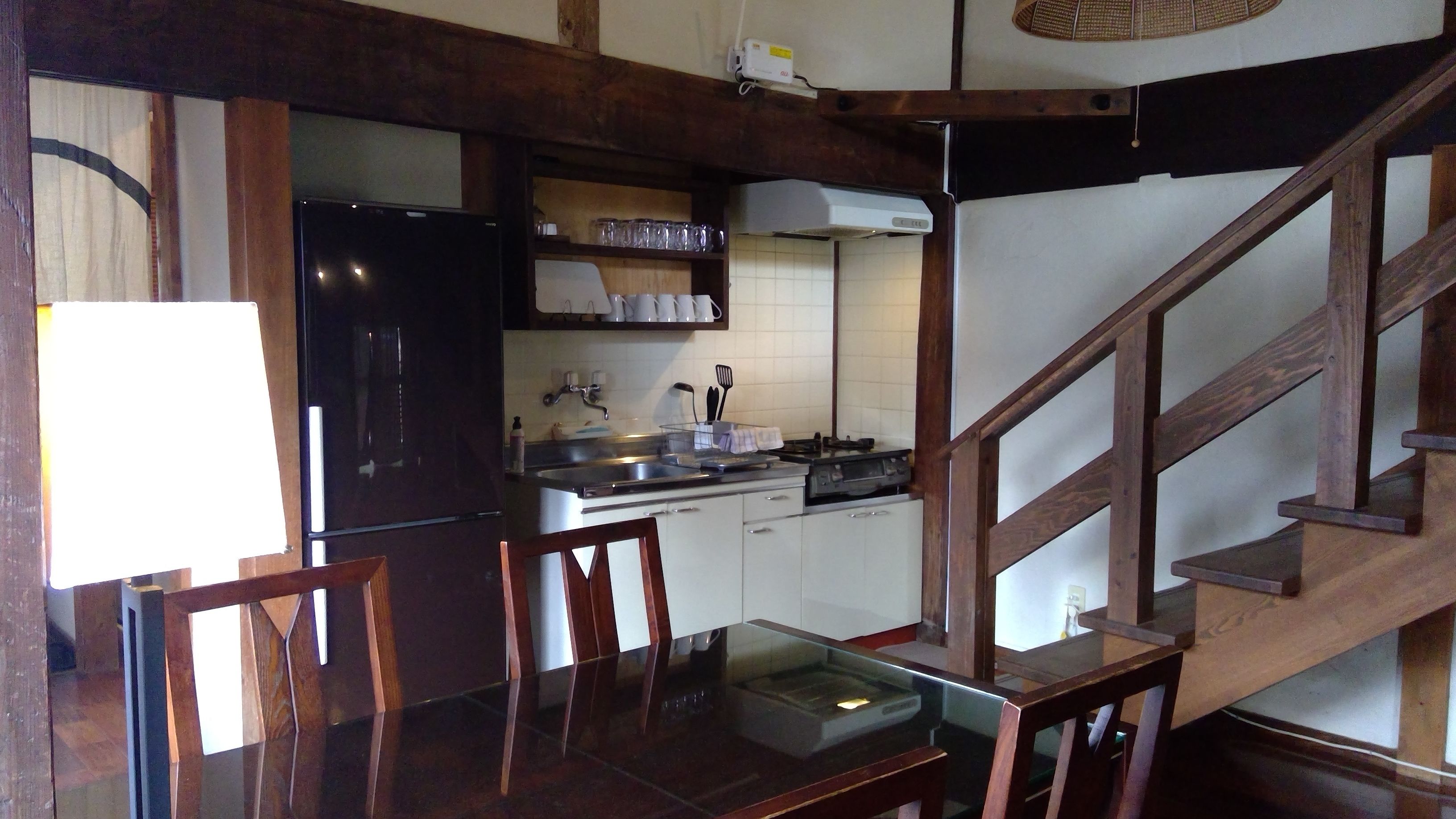 A kitchen with wooden beams, a refrigerator, a stove, and a dining table with chairs.