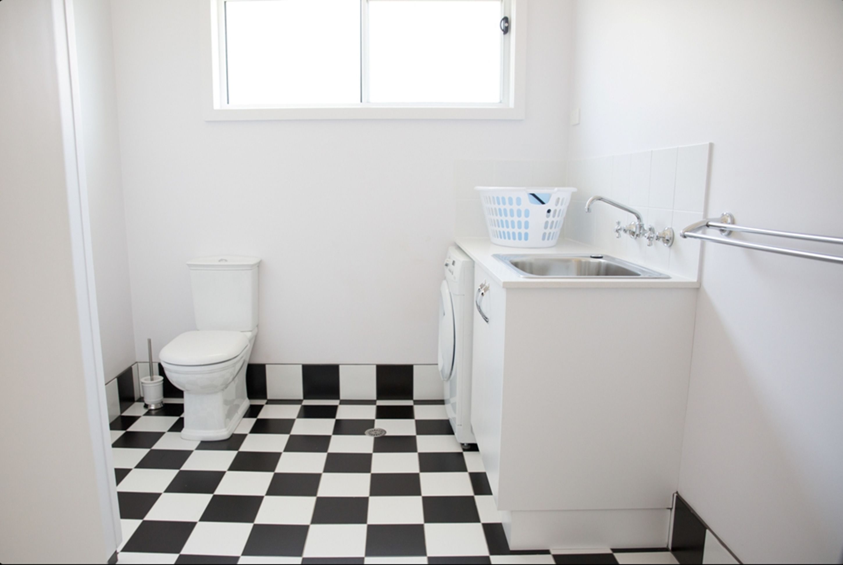 A small, clean bathroom with a toilet, washing machine, and sink.