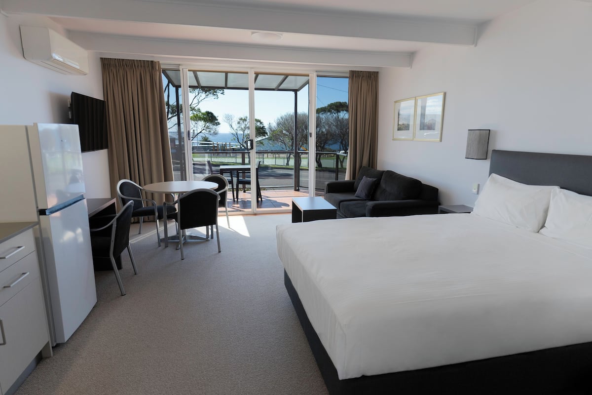 Ein Hotelzimmer mit Bett, Schreibtisch, Stuhl, Sofa und einem Balkon mit Aussicht.