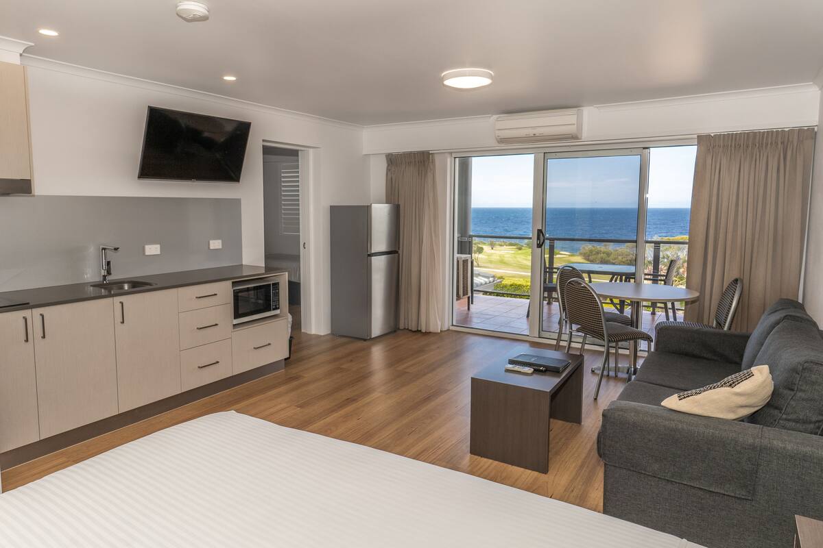 Ein modernes Hotelzimmer mit einer Küche, einem Essbereich und einem Balkon mit Meerblick.