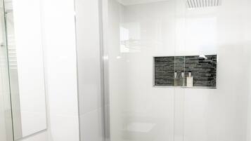 A modern bathroom with a black countertop sink, a glass shower enclosure, and a wall-mounted mirror.