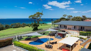 A pool area with lounge chairs and a view of the ocean. - Amooran Oceanside (Narooma)