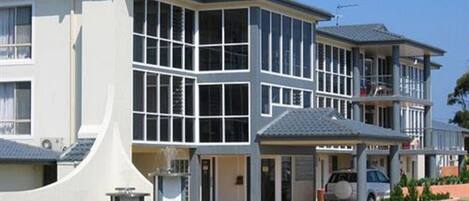 A modern two-story house with large windows, a covered porch, and a well-maintained lawn.