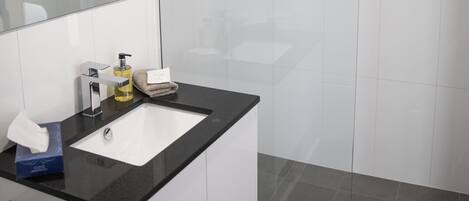 A modern bathroom with a large mirror, a black countertop sink, and a glass shower enclosure.