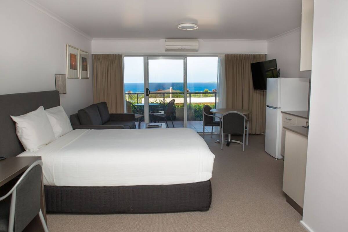 Ein Hotelzimmer mit Bett, Schreibtisch, Stuhl, Fernseher und Meerblick.
