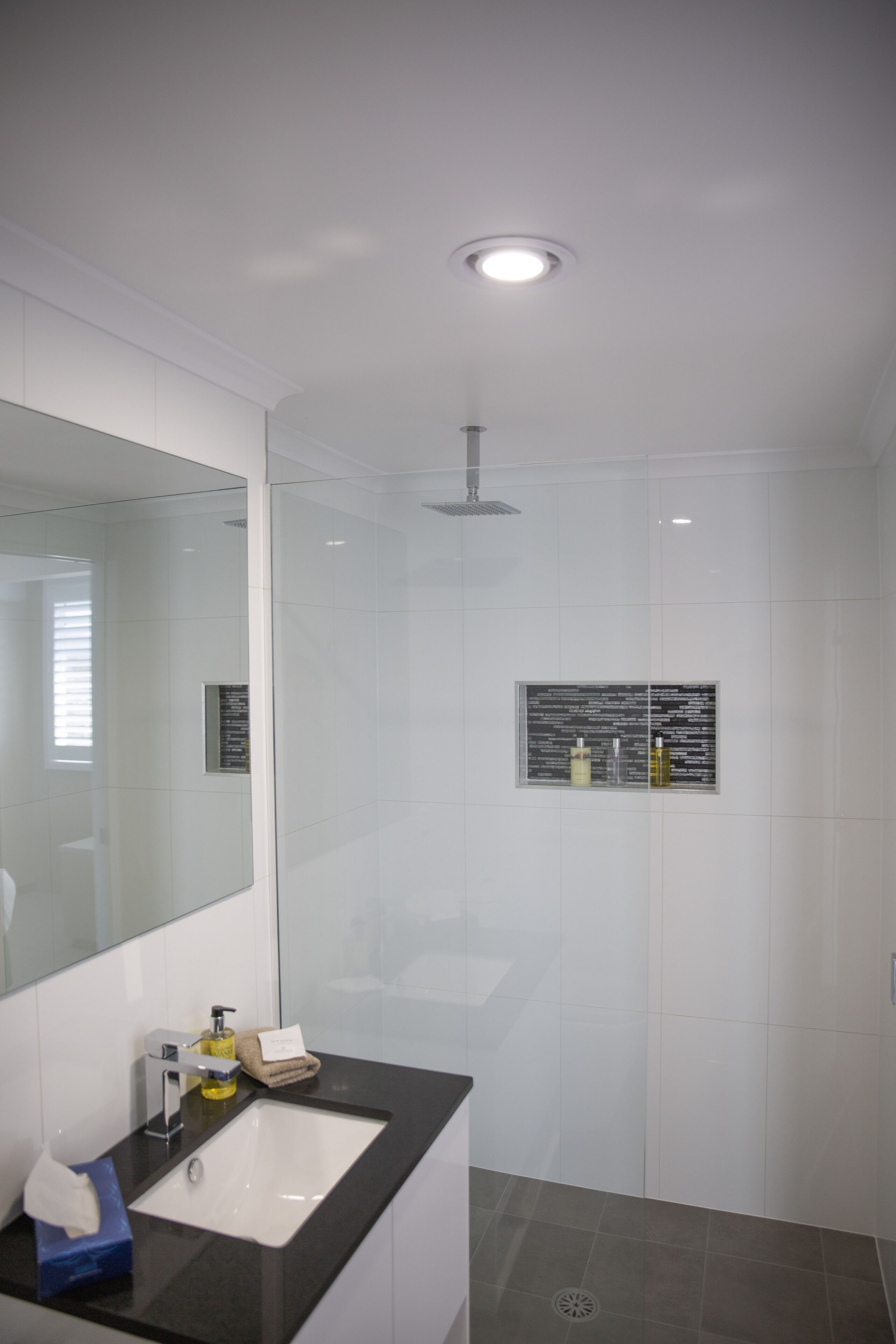 A modern bathroom with a glass shower enclosure, a white sink, and a large mirror.