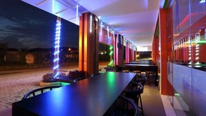 An outdoor dining area with a long table and chairs, illuminated by colorful lights. - Miyana Hotel (Medan)
