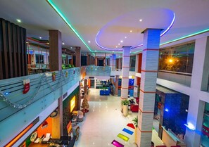 A multi-level hotel lobby with a central staircase, seating areas, and a Christmas tree. - Miyana Hotel (Medan)