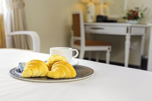 A breakfast setting with croissants on a plate, a cup of coffee, and a white tablecloth. - Chalcedony Grand Hotel (Hanoi)