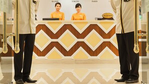 A reception area with a chevron-patterned counter, clocks, and a chandelier. - Chalcedony Grand Hotel (Hanoi)