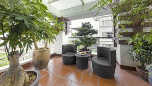 A balcony with wicker furniture, potted plants, and a view of the city. - Chalcedony Grand Hotel (Hanoi)