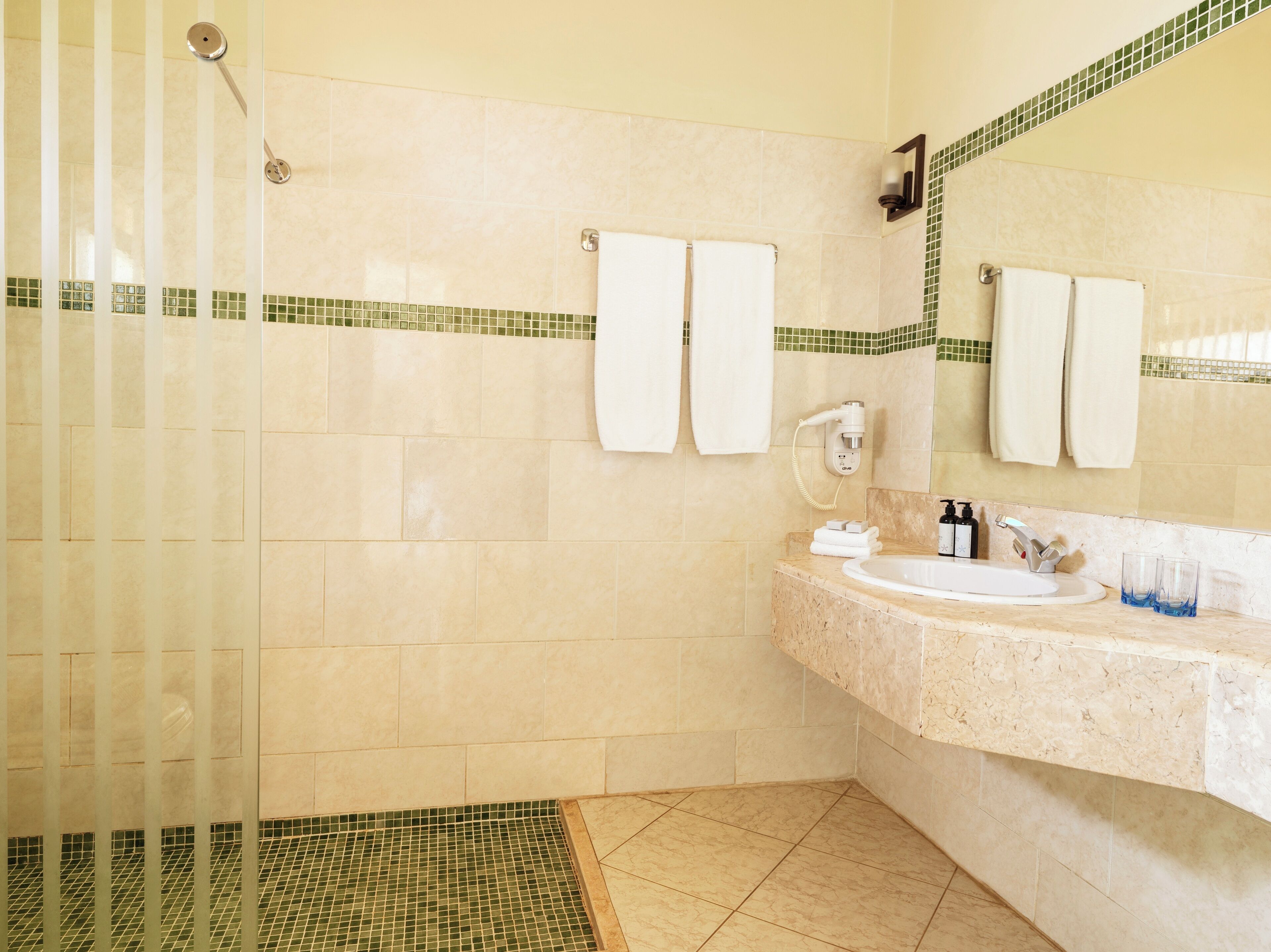Une salle de bain avec une douche, un lavabo et deux porte-serviettes.