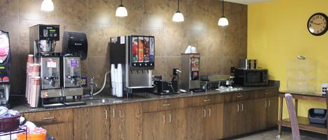 Een kitchenette met een koffieapparaat, magnetron en diverse apparaten.