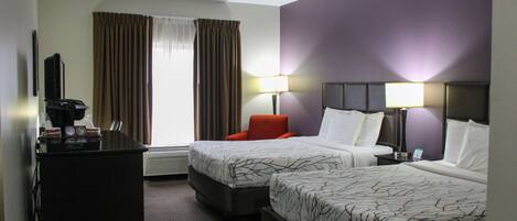 A hotel room with two beds, a desk, a chair, and a television.