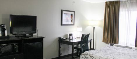 A hotel room with two beds, a desk with a chair, a television, and a lamp.