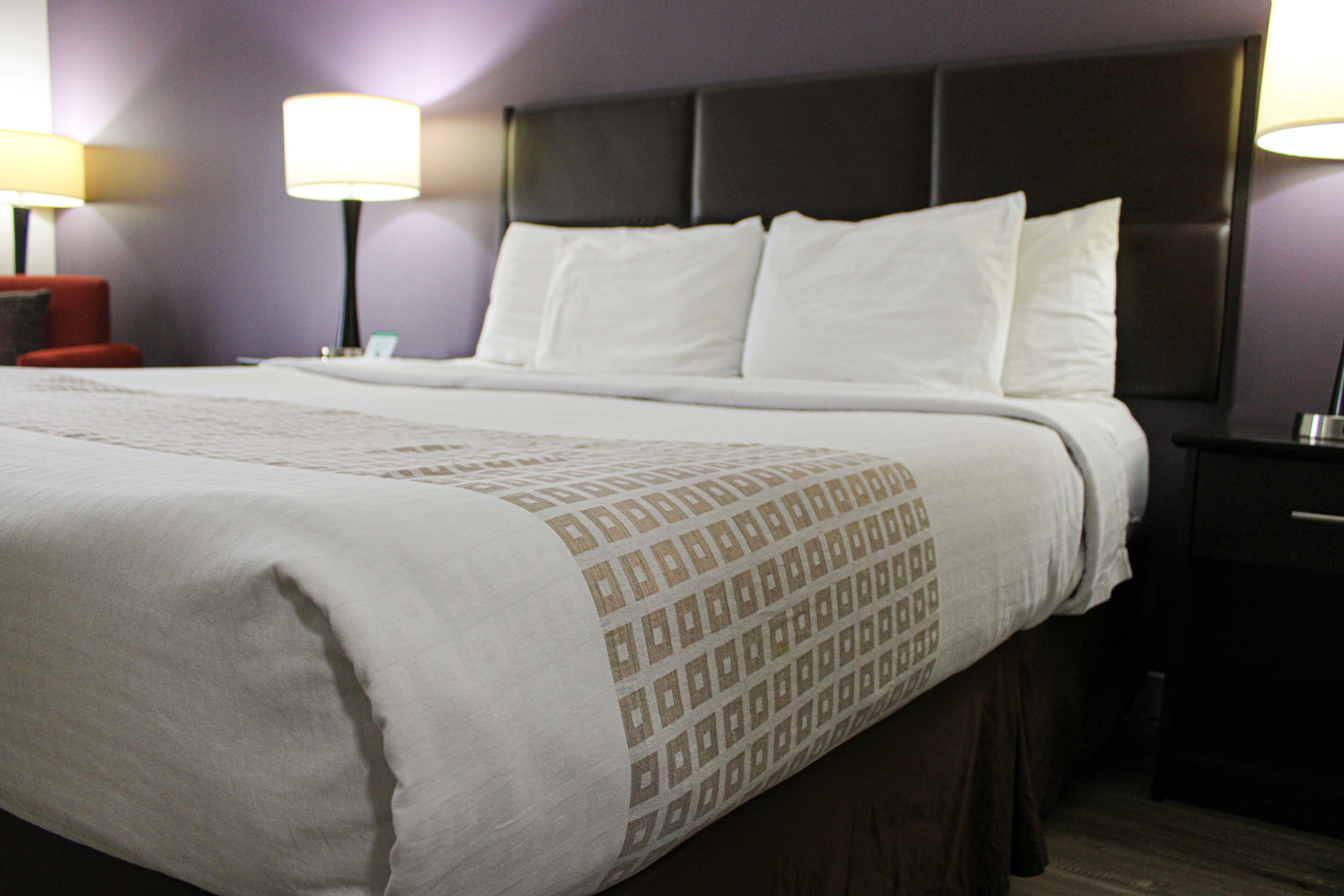 A neatly made bed with a patterned bedspread, a dark headboard, and two bedside lamps.