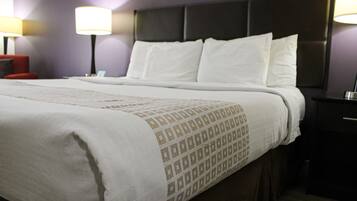 A neatly made bed with a patterned bedspread, a dark headboard, and two bedside lamps.