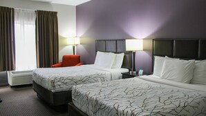 Une chambre d’hôtel avec deux lits, une chaise et une table de chevet avec des lampes.